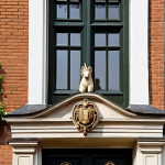 **Prompt:** A quintessential Dutch canal house facade under soft, warm sunlight. Highlight a highly detailed, symbolic 'gevelsteen' (facade stone) prominently displayed, such as one featuring a unicorn or a traditional trade emblem. The house should boast a classic step or bell gable adorned with an intricately carved 'makelaar' (finial), perhaps a lion's head or a fruit basket, showcasing artisanal craftsmanship. Emphasize the texture of weathered bricks, the fine lines of a traditional wooden front door with elegant ironwork, and the overall historical charm, evoking a sense of enduring stories and regional identity.